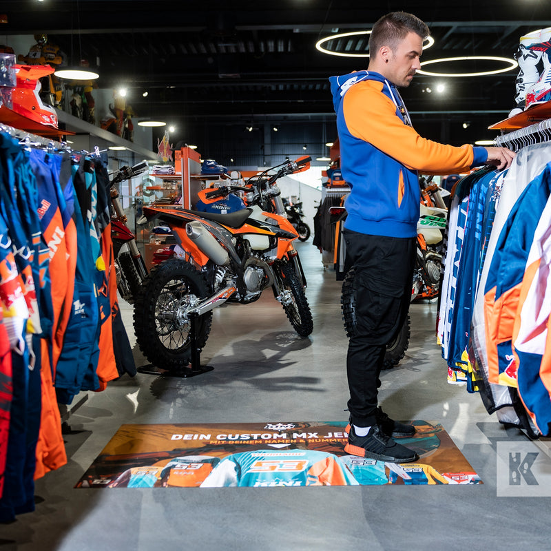 Biker jackets and motorbikes in a showroom with an advertising mat