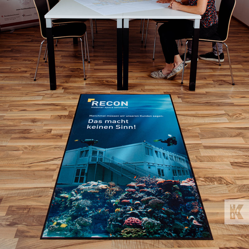 Recon branded floor mat with deep sea divers in an underwater scene, positioned in an office