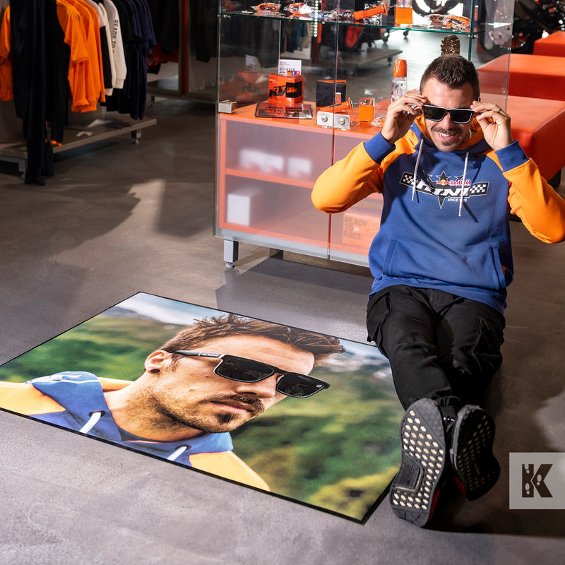 Man in Red Bull top sat on printed mat in KTM store