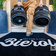 Thirsty bloke carries two kegs of beer into a building across a Bierol branded floor mat