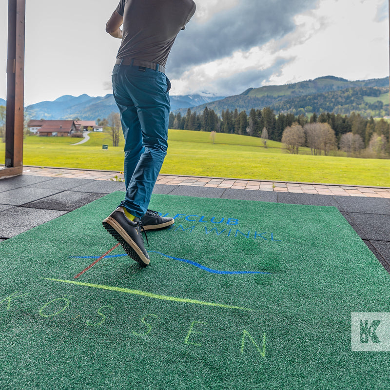 Man smashing a golf ball into the sky on a driving range with a branded T-Off mat under foot