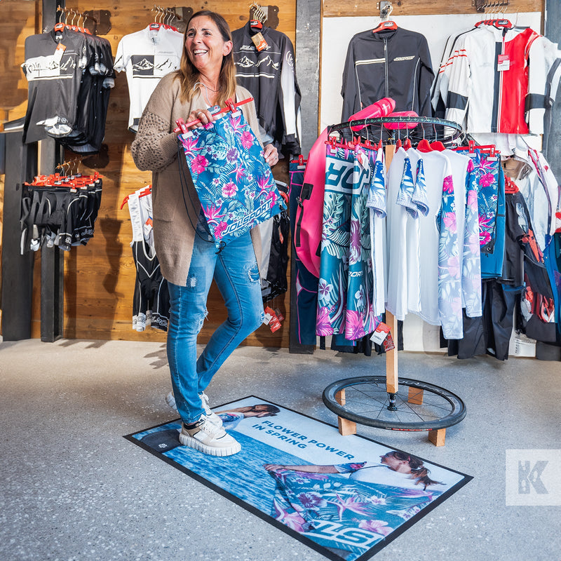 Flower Power motif on a printed advertising mat with a woman browsing through a clothes rail in store