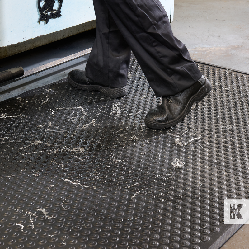 Person wearing black shoes stepping onto a textured mat with Kasp logo.