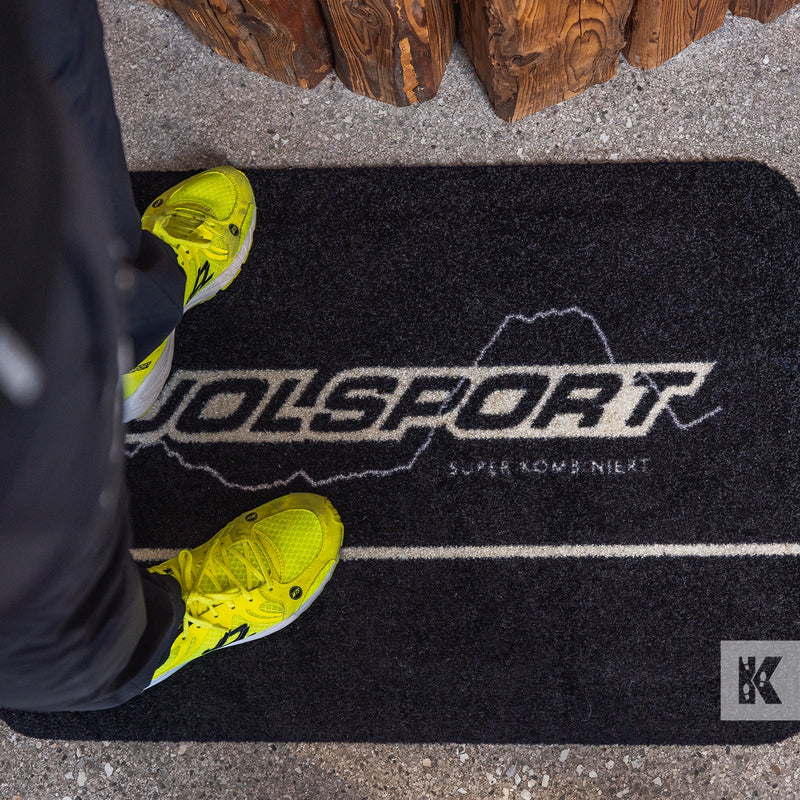 Yellow trainers on a printed mat with Jolsport branding