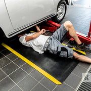 Man working on a car undercarriage while lying on a Kleen-Comfort Safety mat