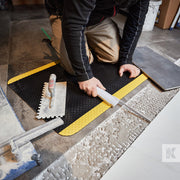 Kleen-Comfort Safety Mat being used by a builder laying floor tiles