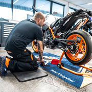 Man fixing a motorbike kneeling on a Kleen-Foam mat