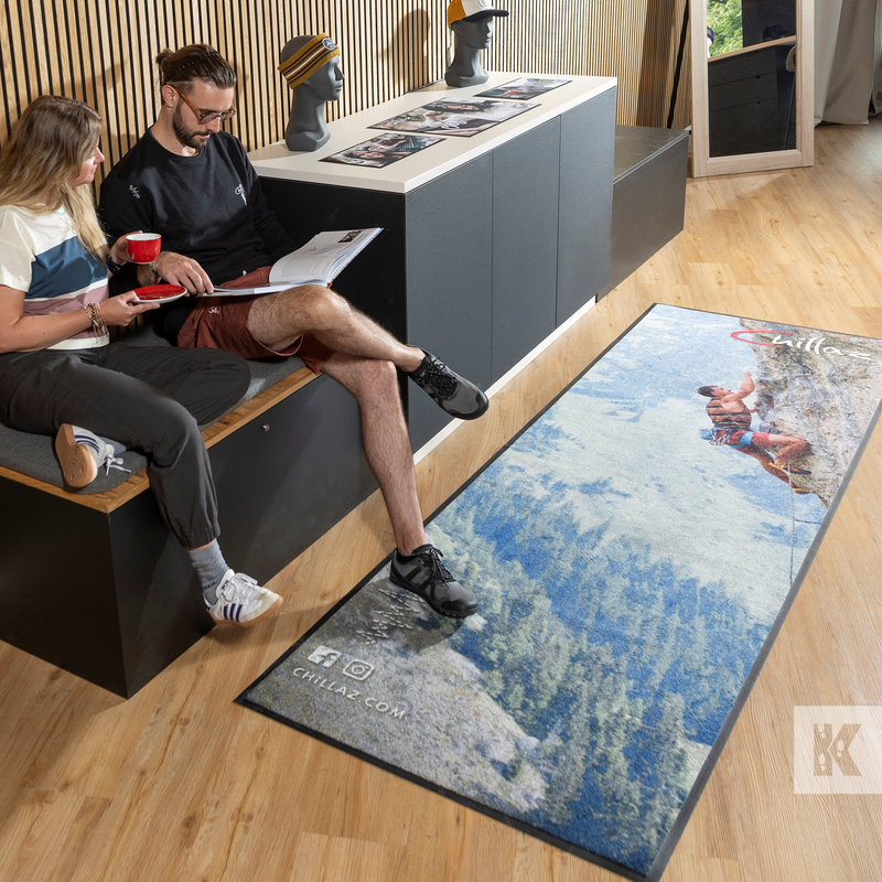 Two people sitting on a bench with a decorative rug featuring a nature scene in the foreground.