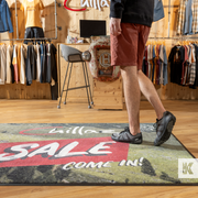 Person standing on a rug with 'Sale' and 'Come In!' text in a clothing store.