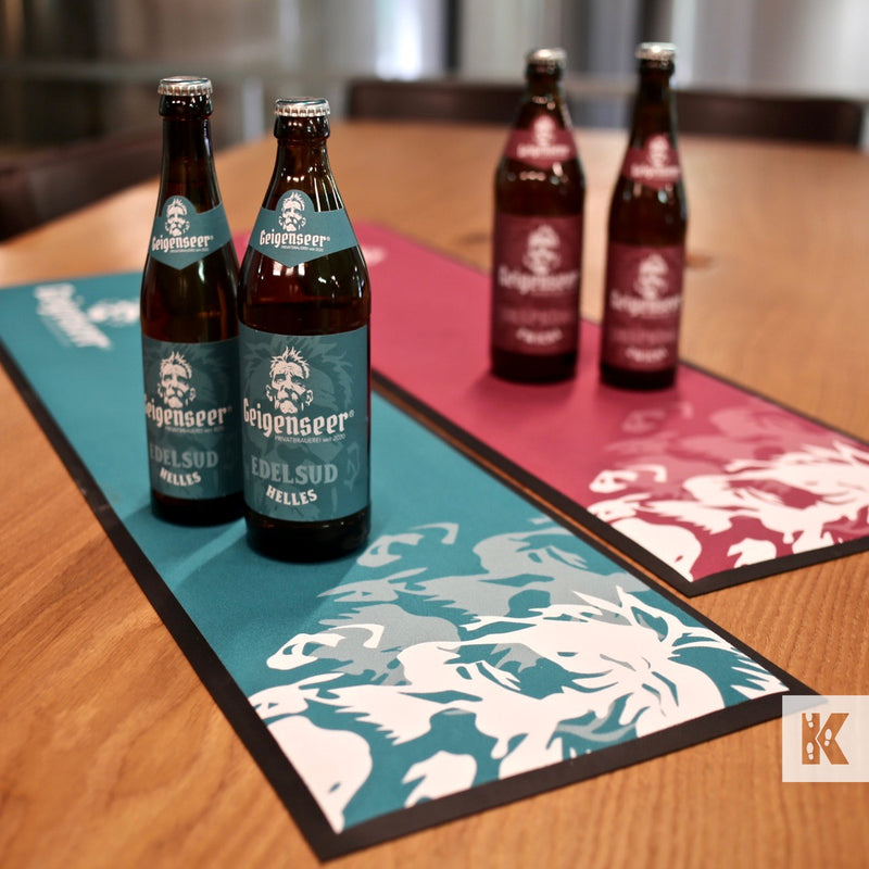 Custom printed bar mats with bottle designs displayed on a table.