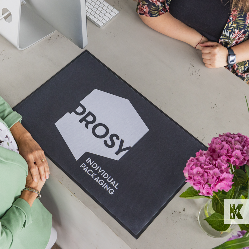 Top down view of 2 ladies discussing over a printed Prosy mat