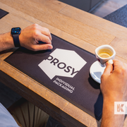 A strong coffee to start the day, with a Prosy branded printed mat on a wooden counter