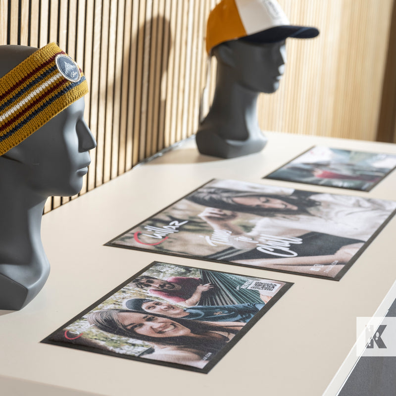 Mannequin heads wearing beanies with printed photos on a table.