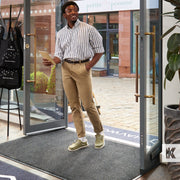 Man walking into a store holding a pamphlet