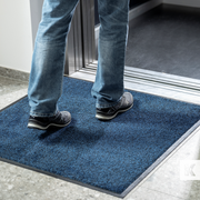 man about to enter a lift with a grey interior, standing on a blue mat
