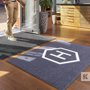 Man walking into a reception area with grey branded mats