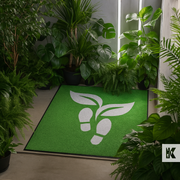 Green doormat with white logo surrounded by plants