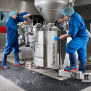 Two men in PPE throwing water over electrical machinery standing on rubber drainage mat