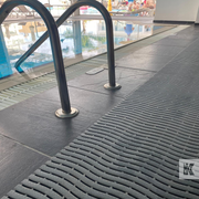 Textured black mat on a pool deck with pool equipment in the background