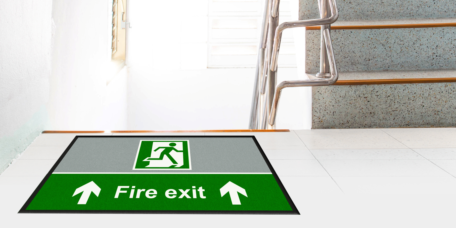 Fire exit safety sign on a printed mat in a white stairway