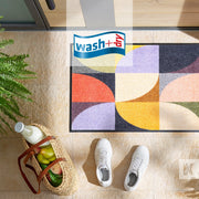 Colourful geometric design n a printed door mat with white sneakers and groceries