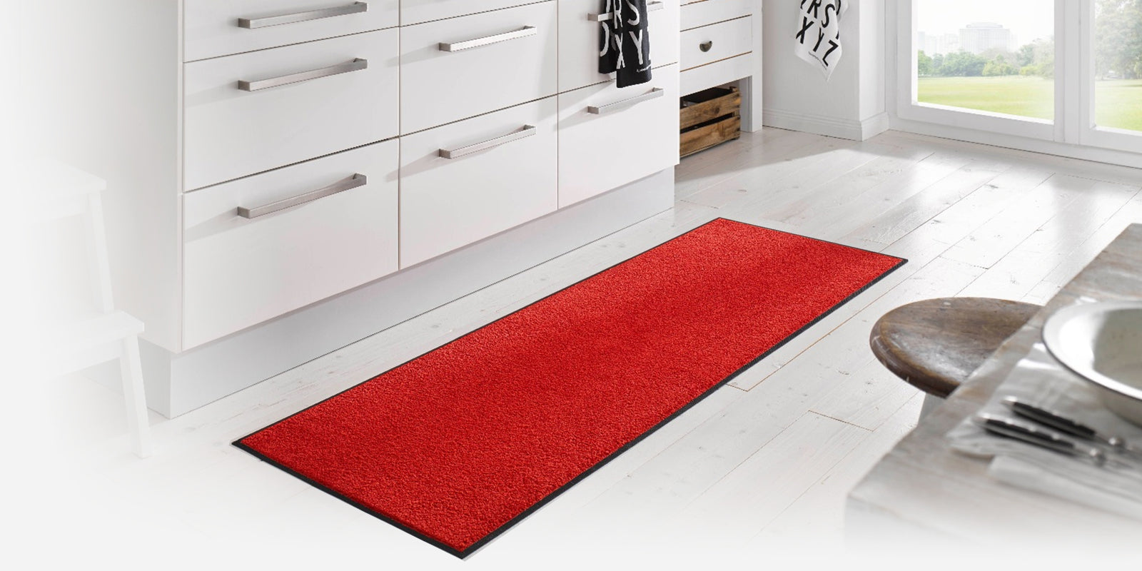Red wash+dry monotone mat in a predominantly white room with table and drawers