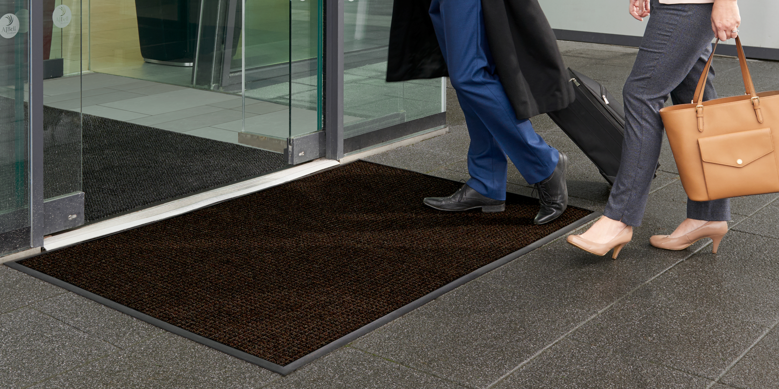 couple entering a hotel lobby with a brown Water-Horse mat